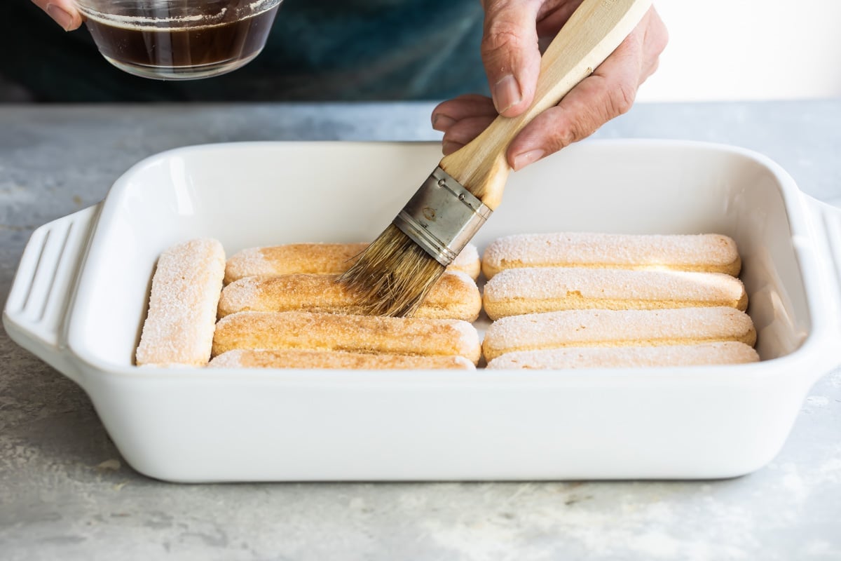 Lady fingers being brushed with rum and coffee.
