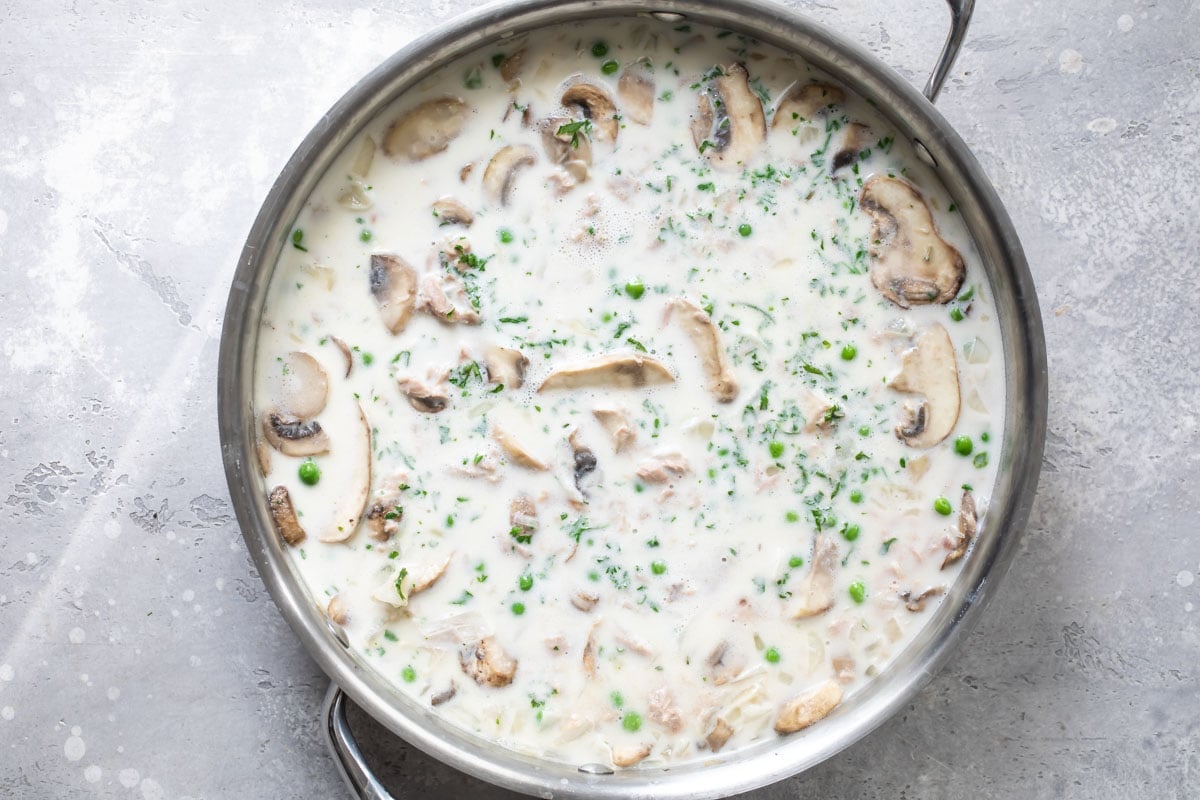 The sauce for tuna noodle casserole cooking in a skillet.