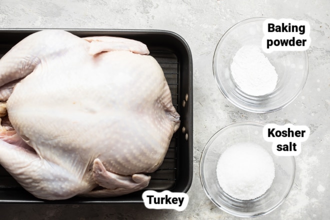 A raw turkey next to bowls of baking powder and salt.