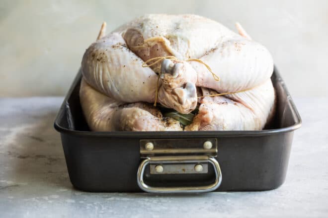 A raw trussed turkey in a roasting pan.