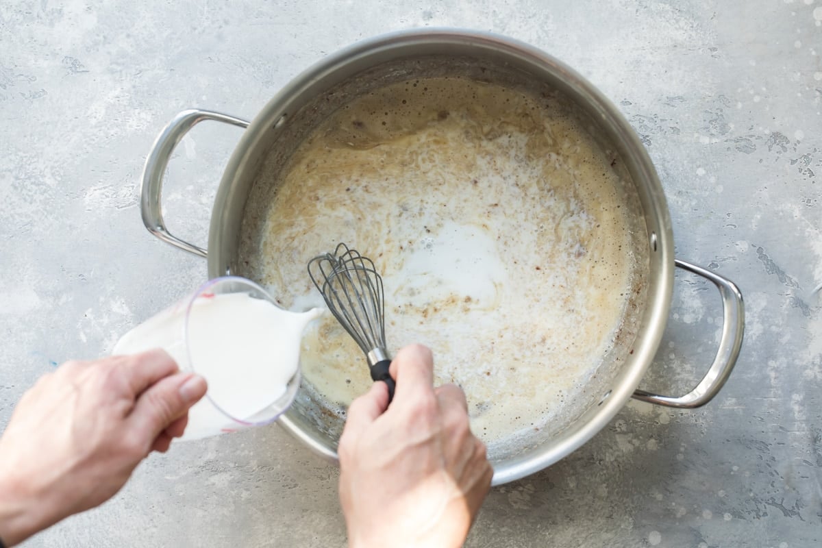 Cream being poured into a silver pot.