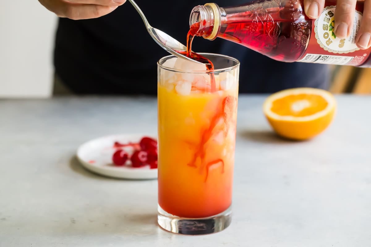 Pouring grenadine into a tequila sunrise.