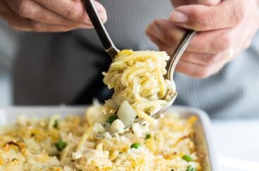 Turkey tetrazzini being scooped out of a white baking dish.