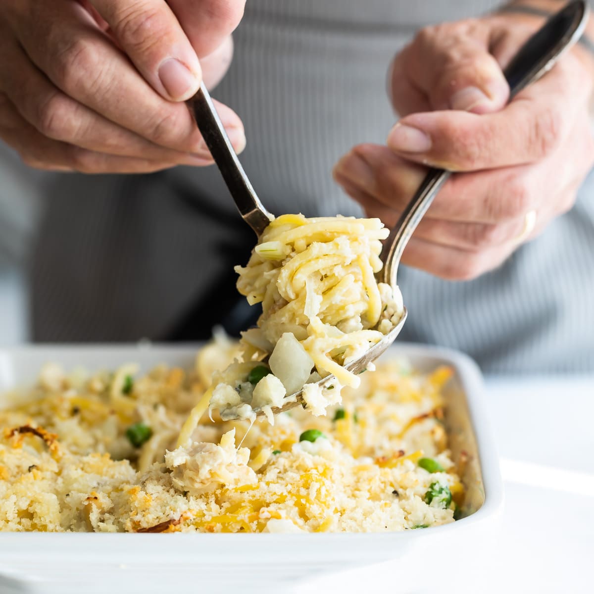 Turkey tetrazzini being scooped out of a white baking dish.