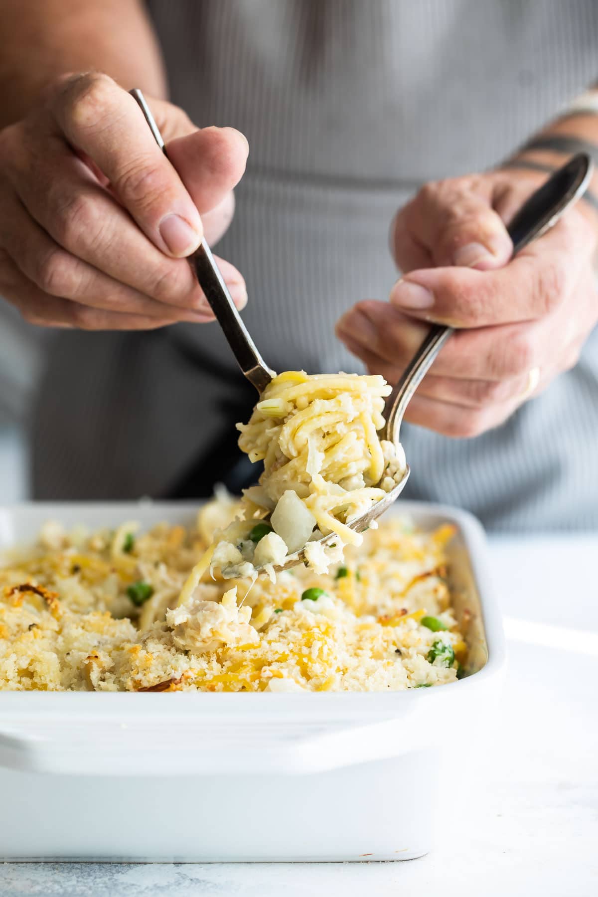 Turkey tetrazzini being scooped out of a white baking dish.