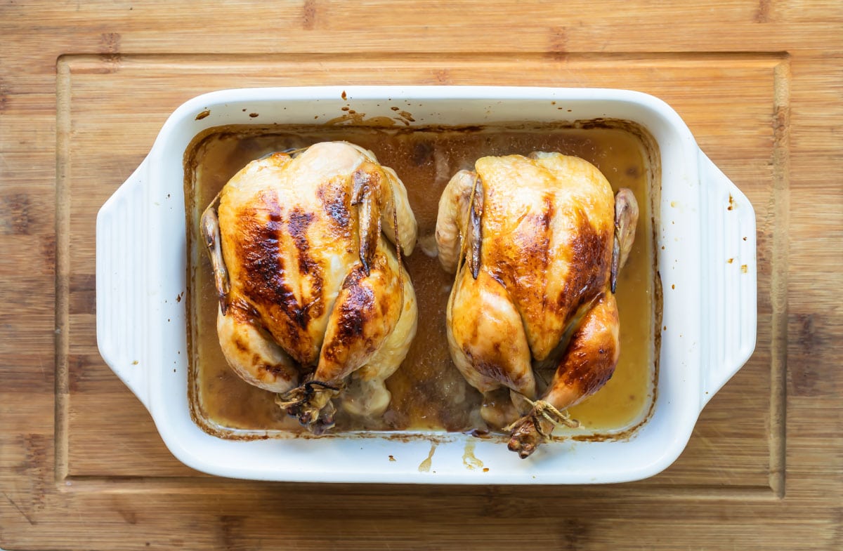 Two cooked Cornish hens in a baking dish.