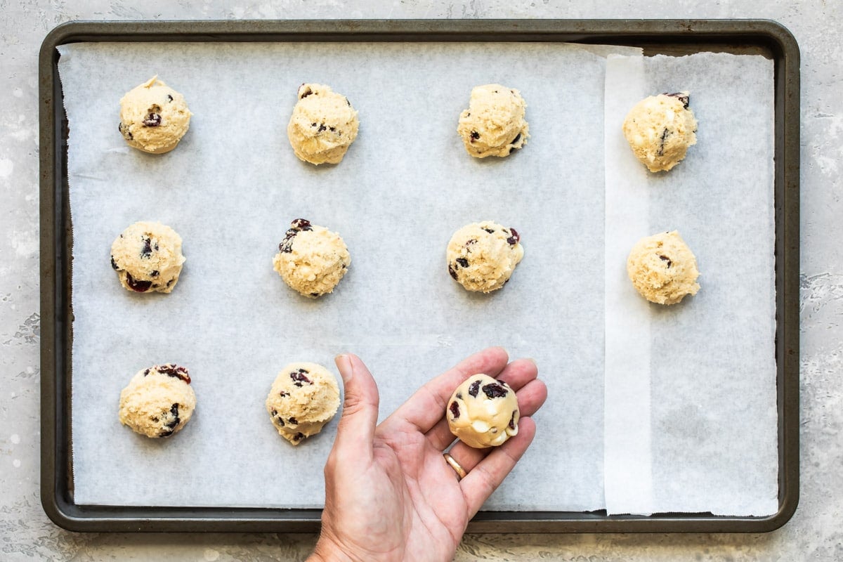 Cranberry cookies with white chocolate on a baking sheet before being baked.