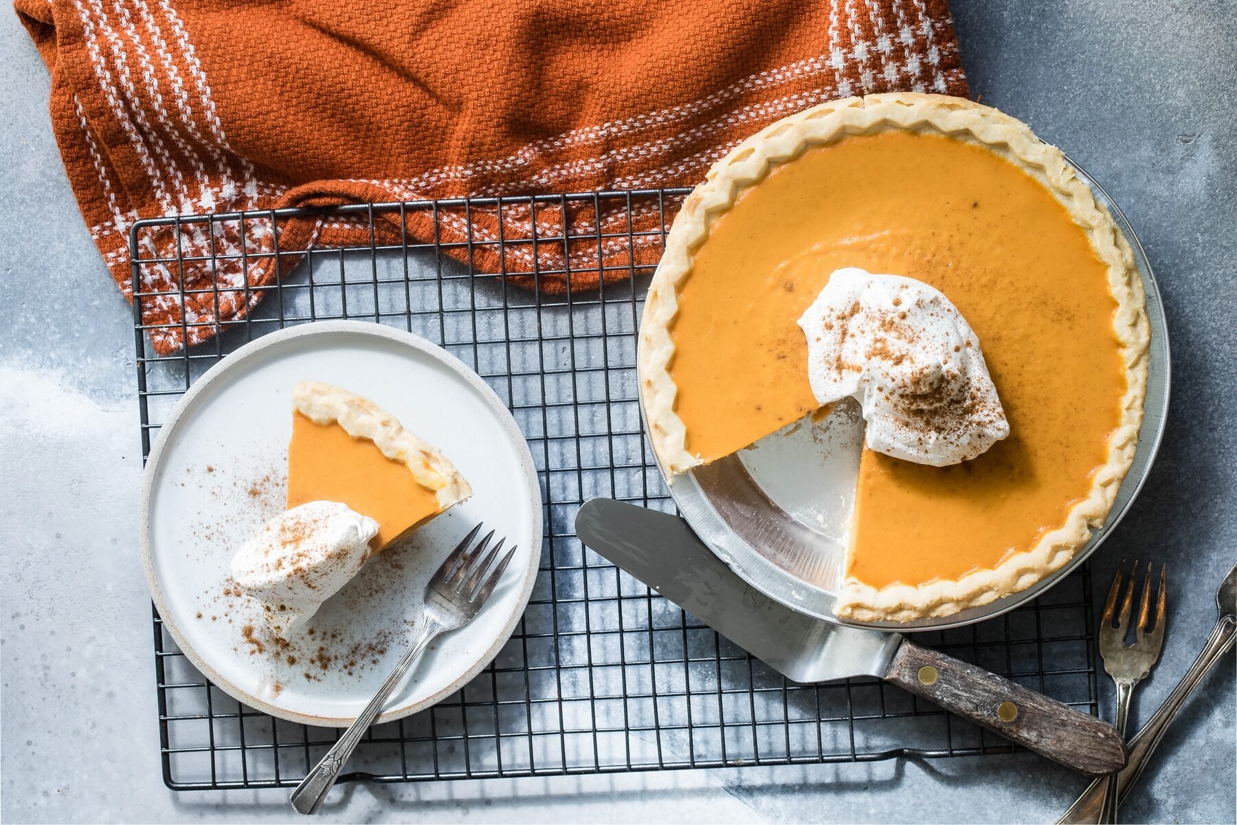 Make ahead pumpkin pie in pie pan with one slice on a white plate with fork.
