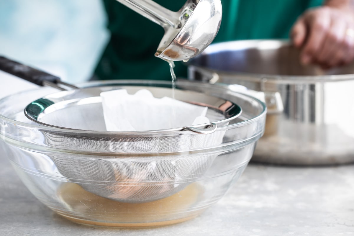 Liquid being strained into a clear bowl.