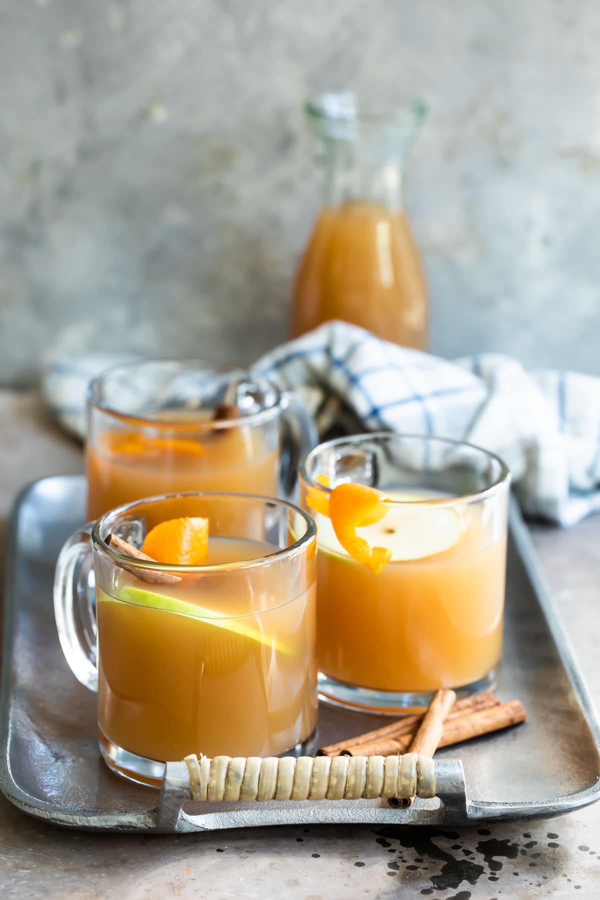 Three glasses of mulled cider on a silver serving platter.