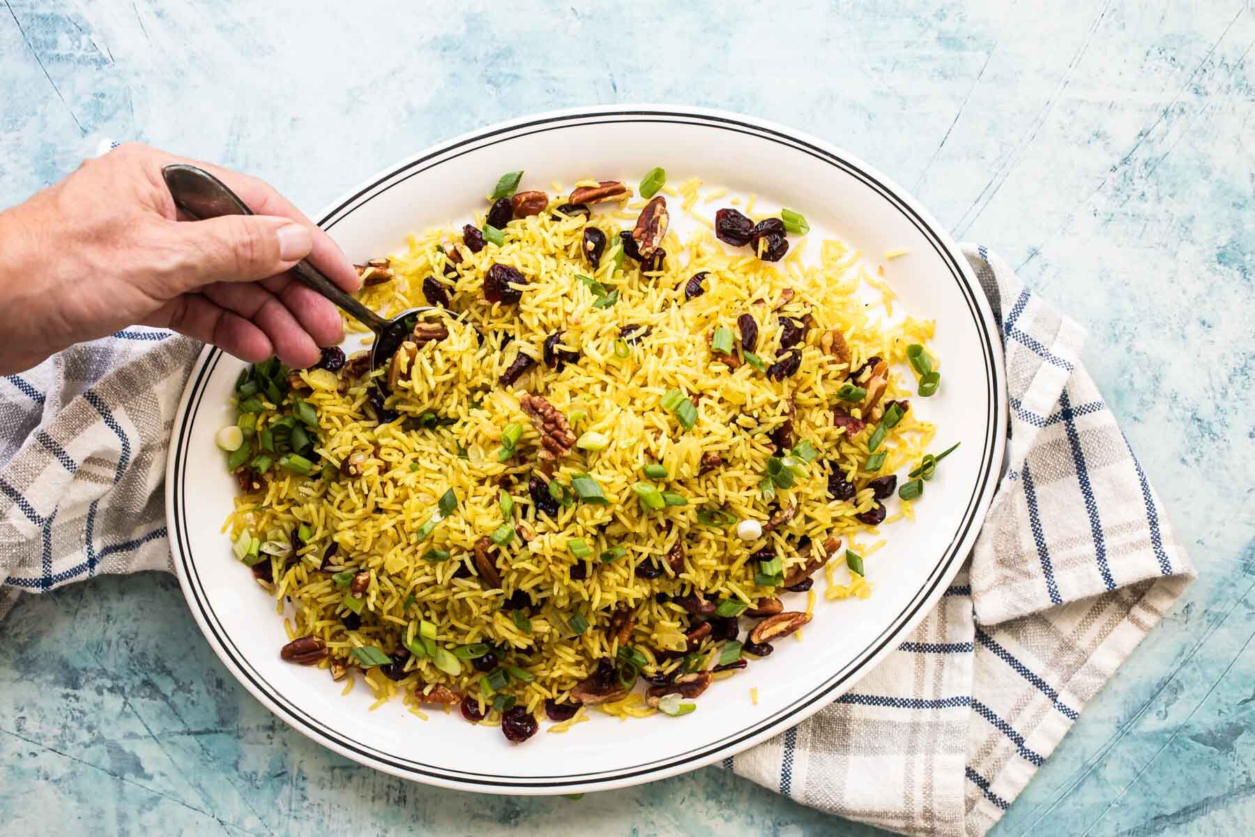 Rice stuffing being scooped off of an oval platter.