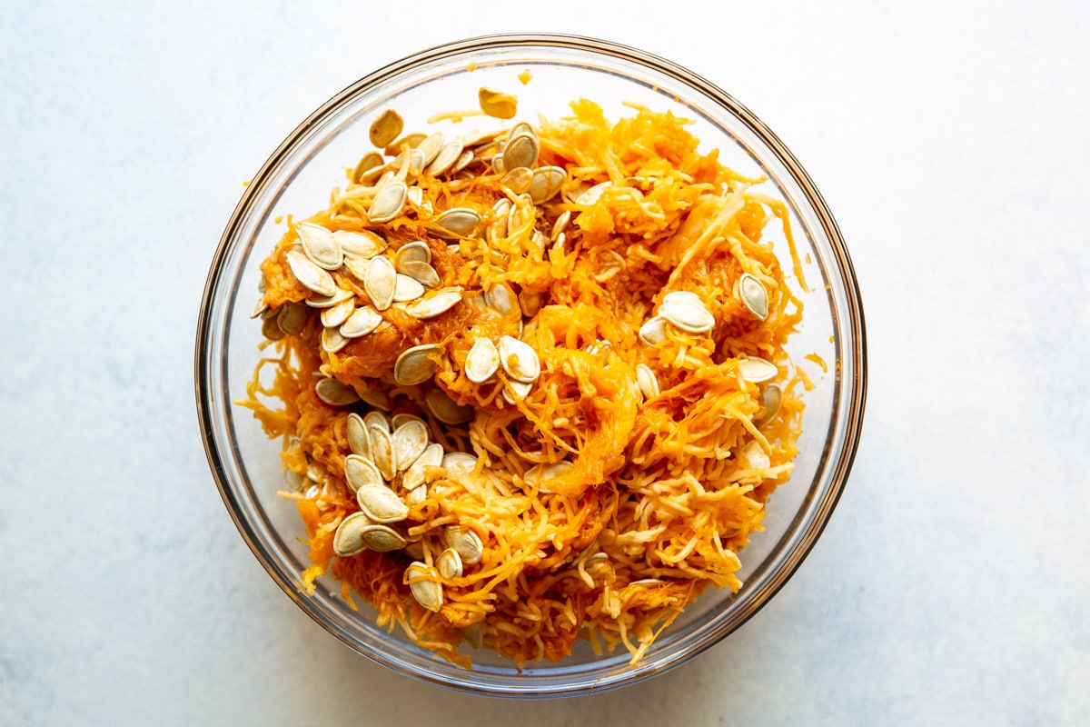 Pumpkin seeds and puree in a clear bowl.