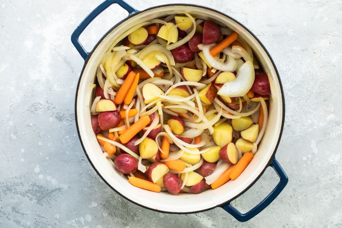 Pot roast vegetables cooking in a Dutch oven.