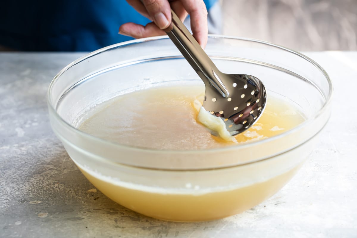Scraping fat layer off chilled turkey broth.