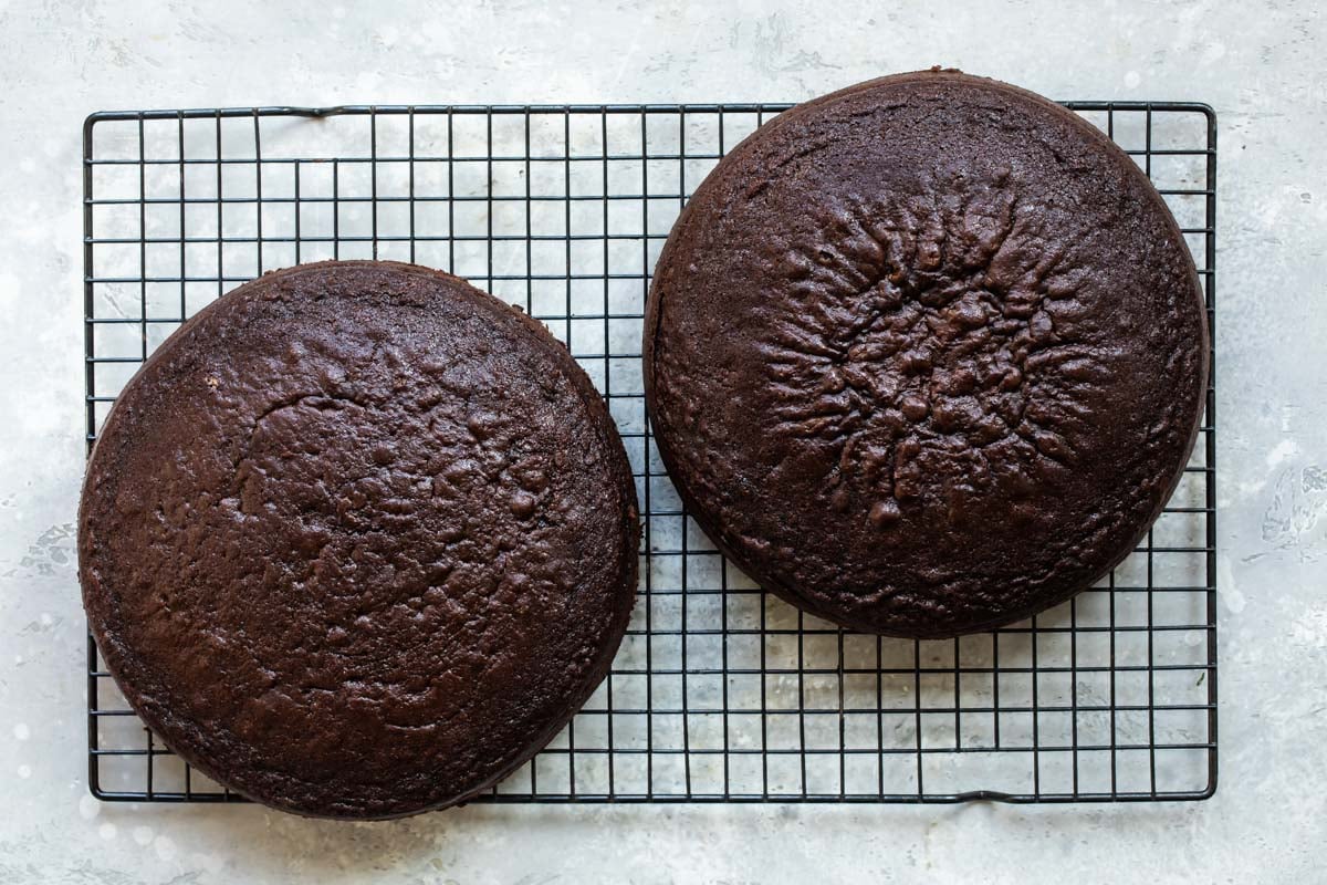Two round chocolate cakes on a cooling rack.