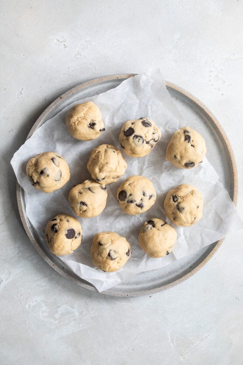 Balls of chocolate chip cookie dough on a gray plate.