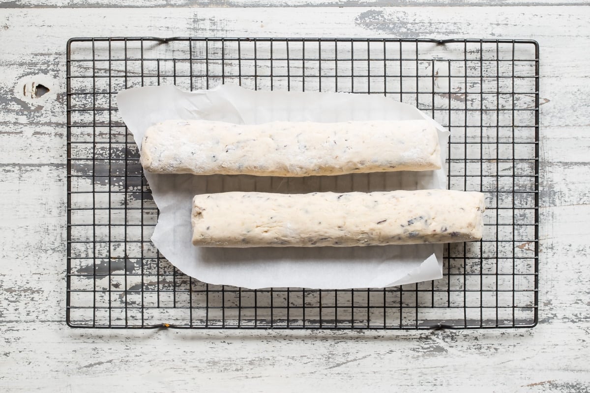 Logs of frozen cookie dough on a cooling rack.