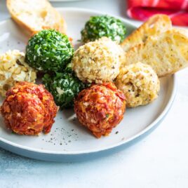 Mini cheese balls on a platter with crackers and crostini.