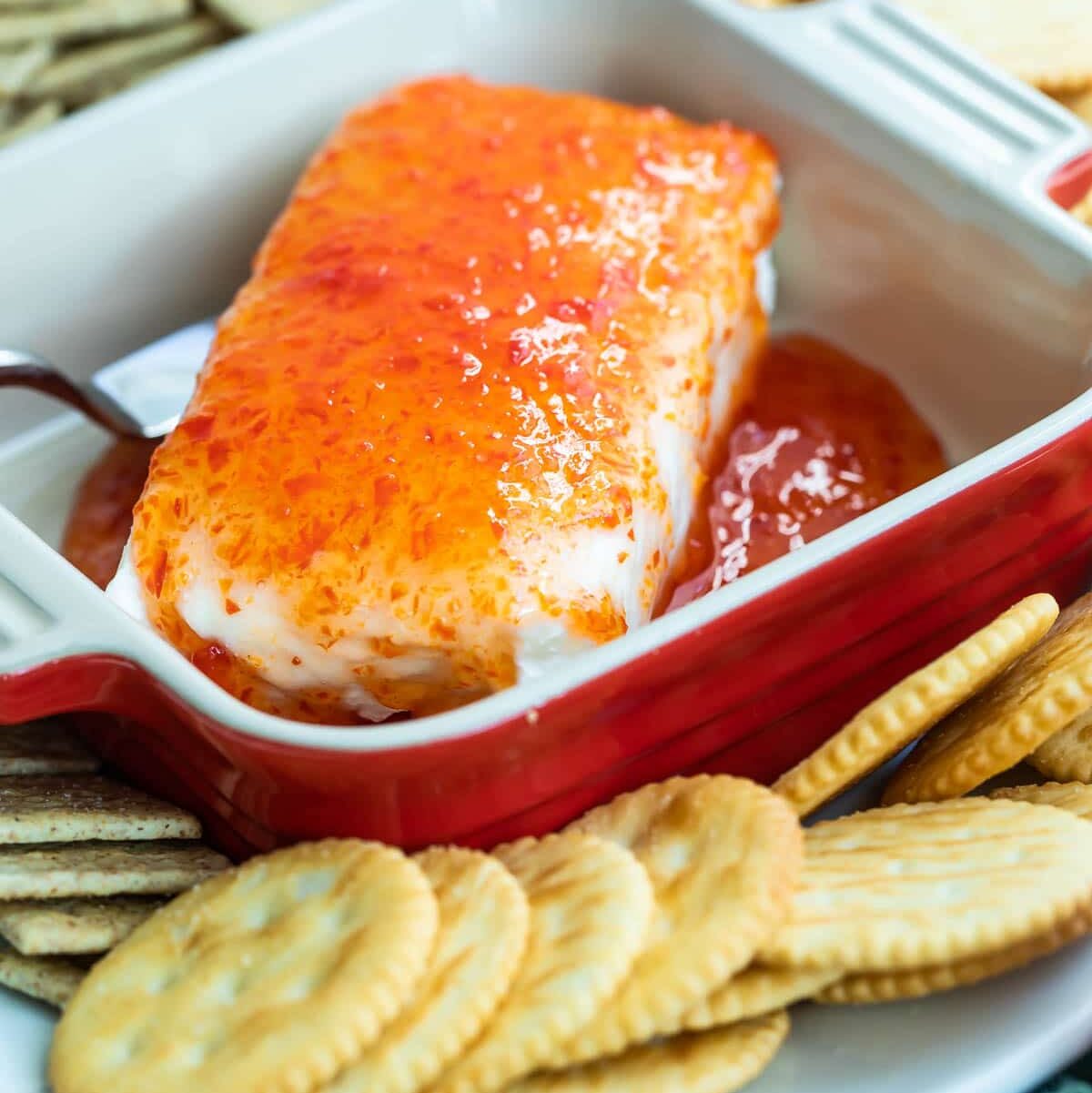 Pepper jelly spooned over a block of cream cheese.
