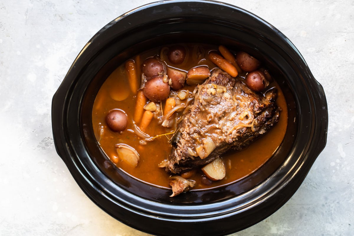 Cooked pot roast in a slow cooker.