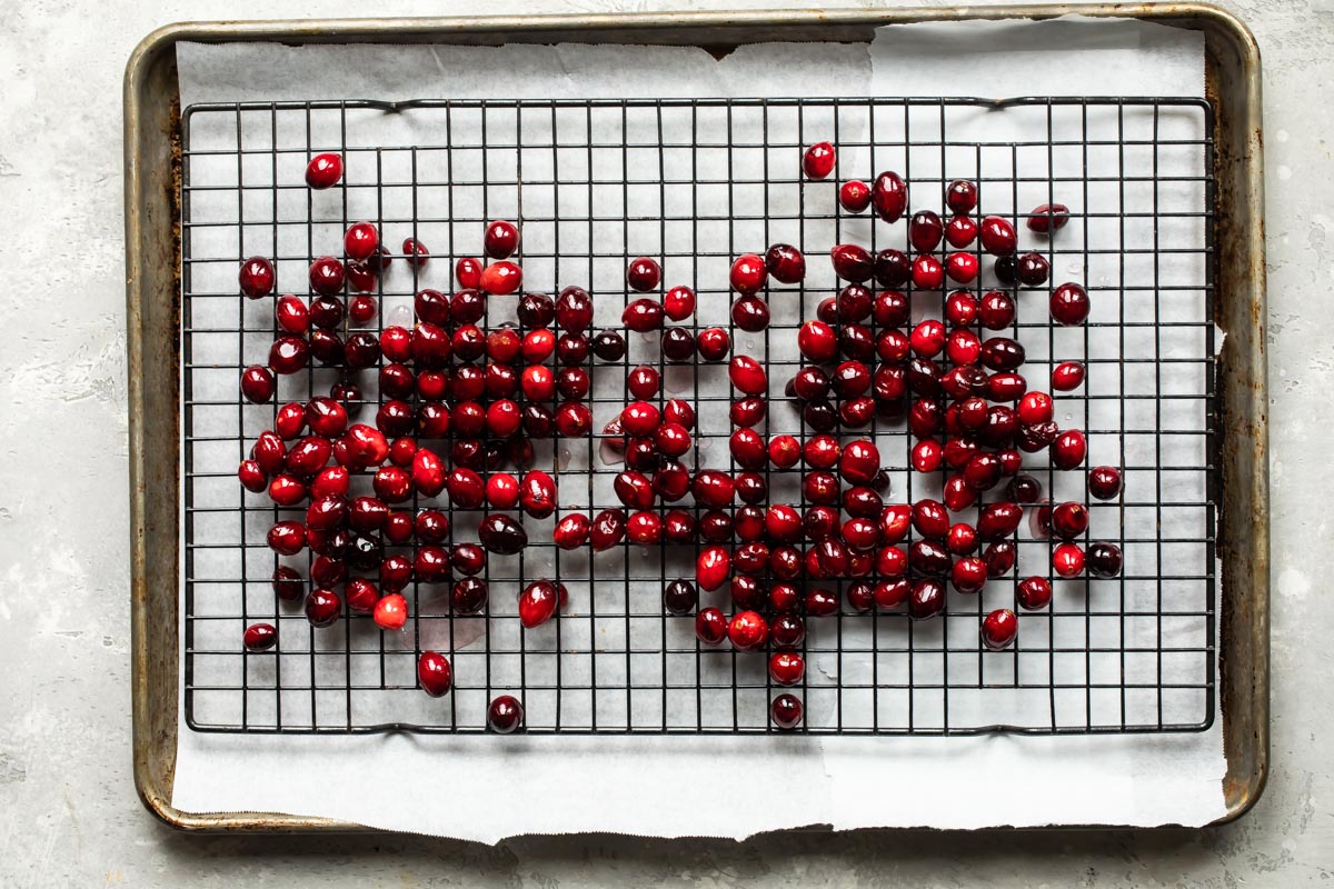 Cranberries on a cooling rack over parchment paper.