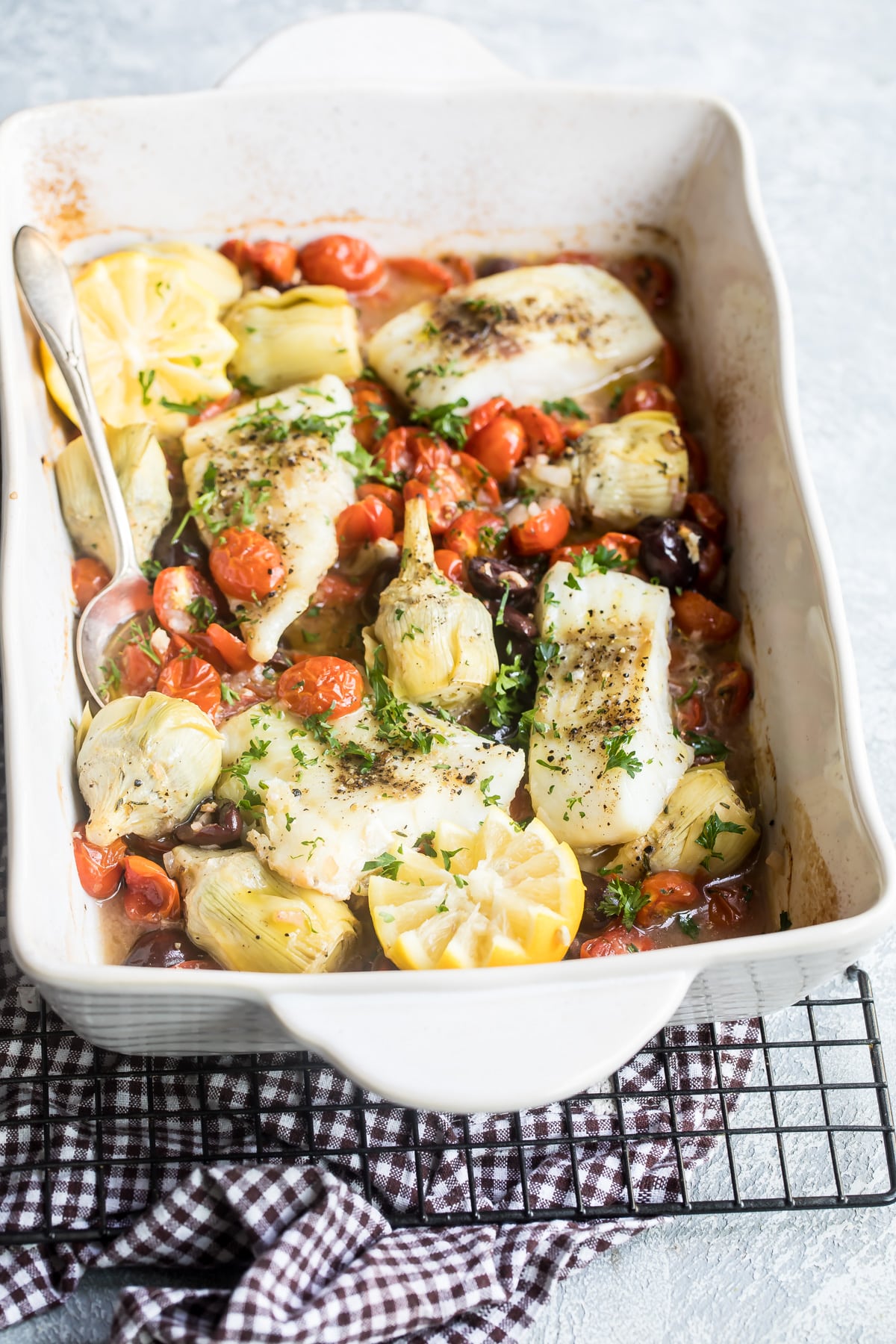 Baked cod in a white baking dish.
