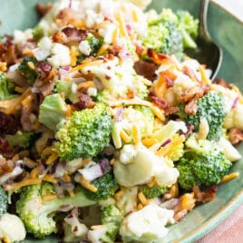 Broccoli salad with bacon and cheese in a green bowl.
