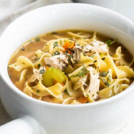 Chicken noodle soup in a white bowl.