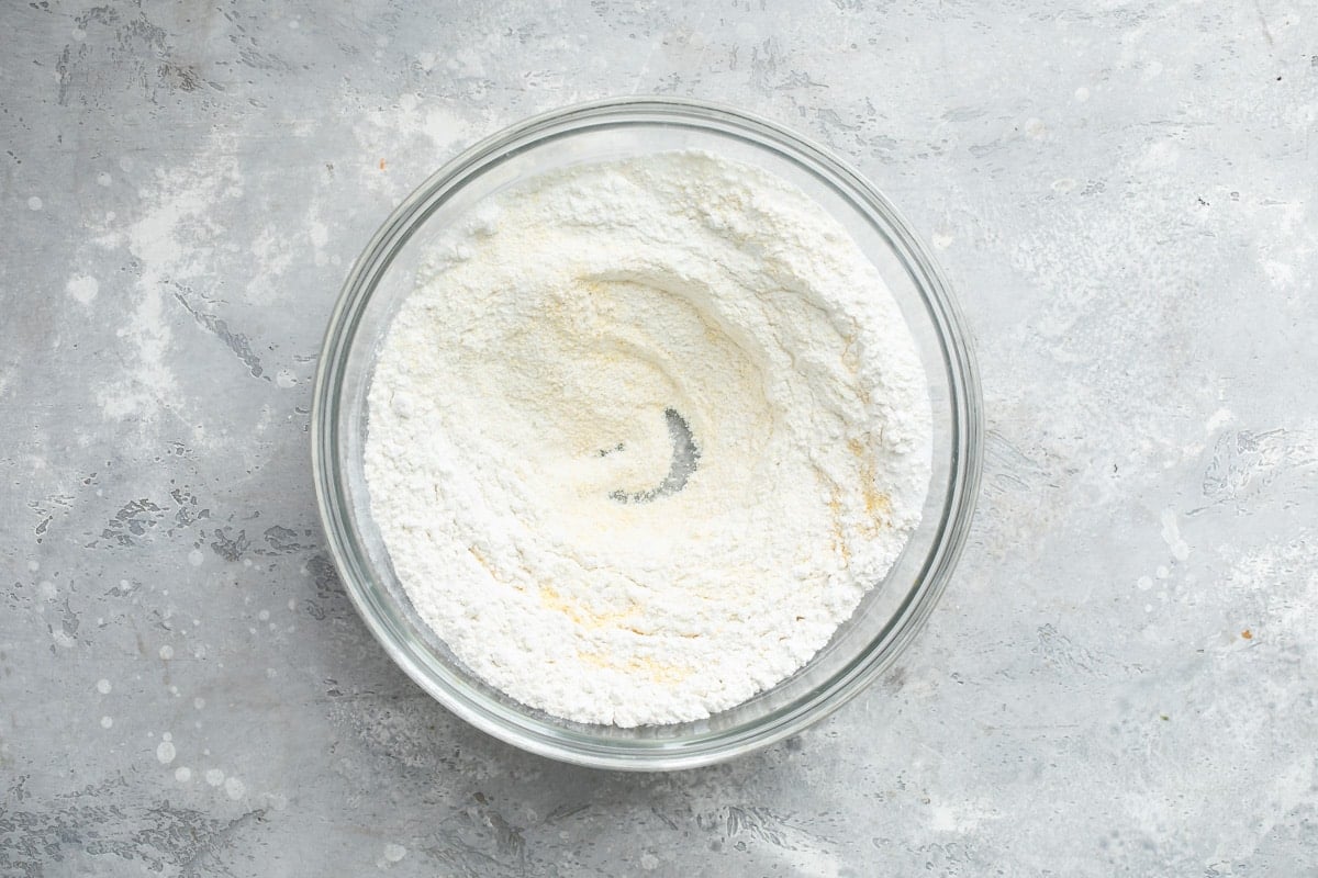 Dry ingredients for cornbread in a clear glass bowl.