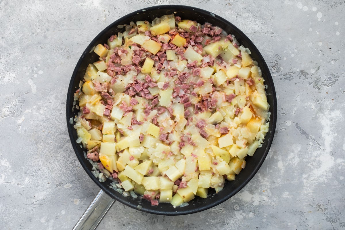 Corned beef hash cooking in a skillet.