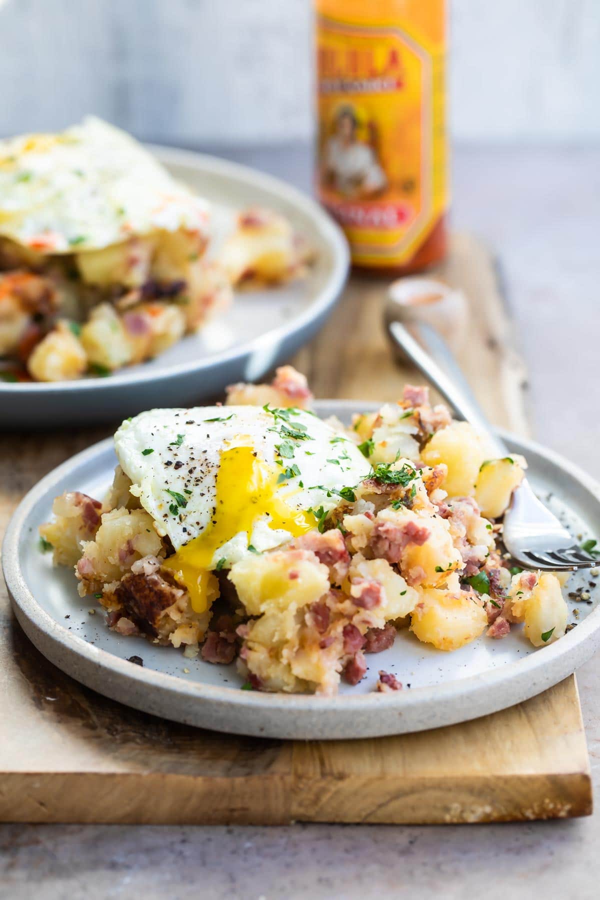 Corned beef hash on a gray plate topped with and egg and parsley.