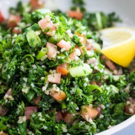 Bulgar tabbouleh in a white bowl with a lemon garnish.