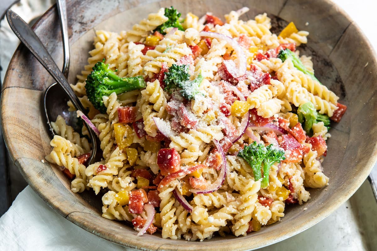 Easy cold pasta salad in a wooden bowl with a serving fork and spoon.