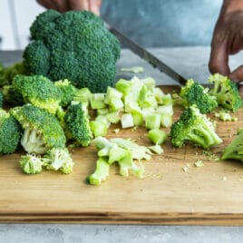 Cut up broccoli on a cutting board.