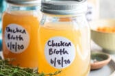 Homemade chicken broth in a jar on a plate.