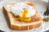 A poached egg on a slice of white toast.