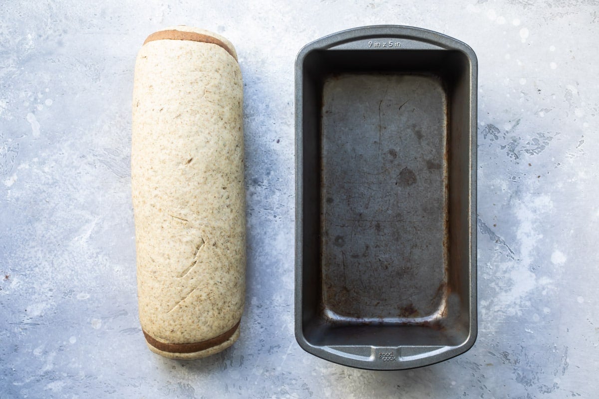 Unbaked bread next to a loaf pan.