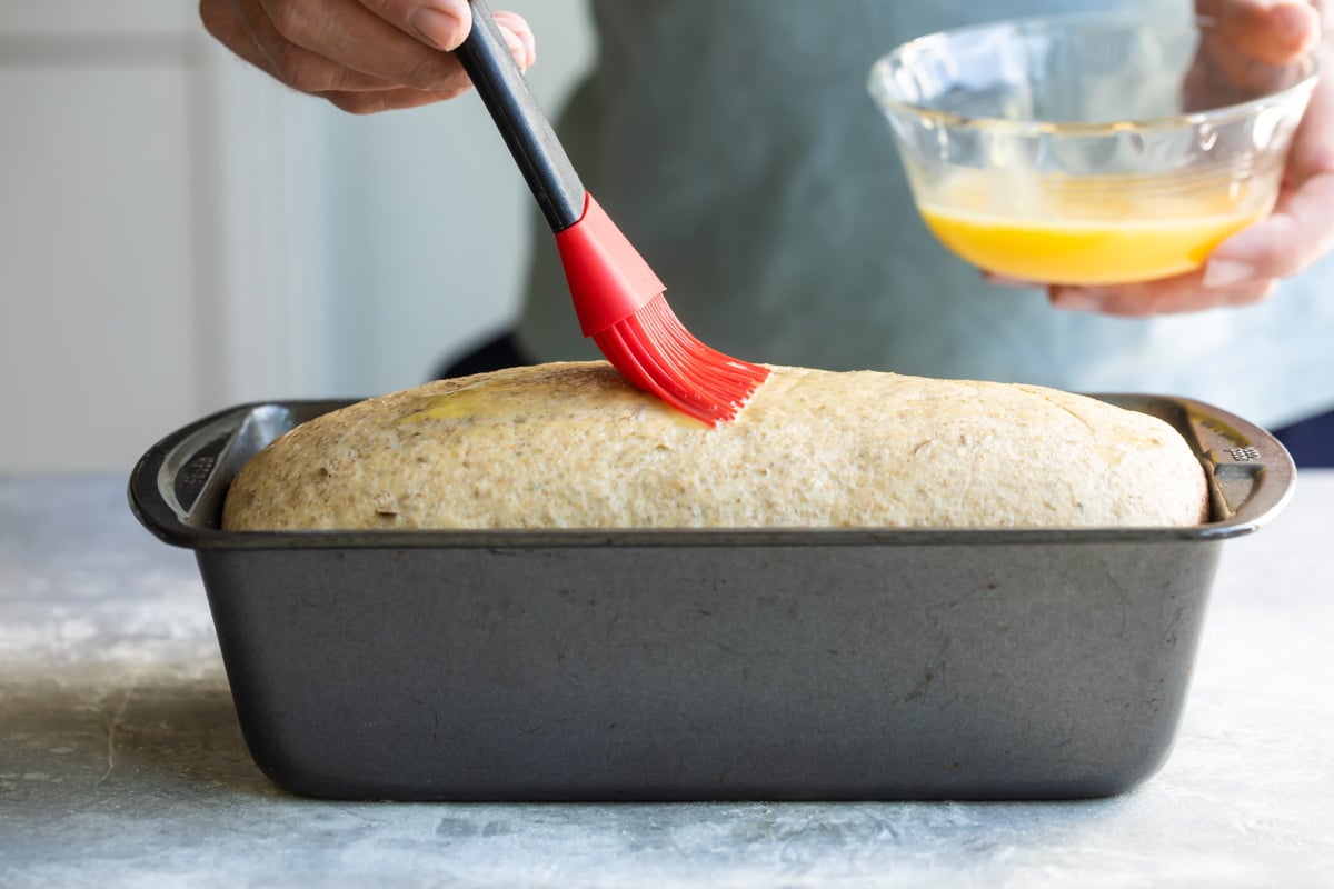 Brushing a loaf of bread with melted butter.