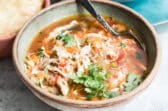 One bowl of Mexican chicken soup with toppings nearby.