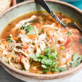 One bowl of Mexican chicken soup with toppings nearby.