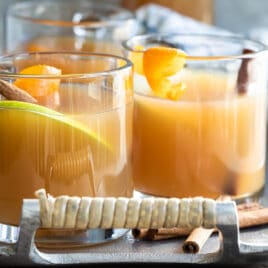 Three glasses of mulled cider on a silver serving platter.
