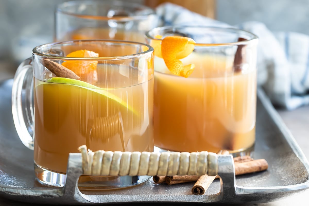 Three glasses of mulled cider on a silver serving platter.