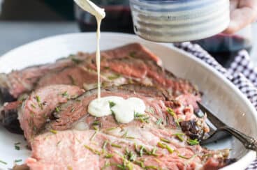 Mustard cream sauce being drizzled over a prime rib.