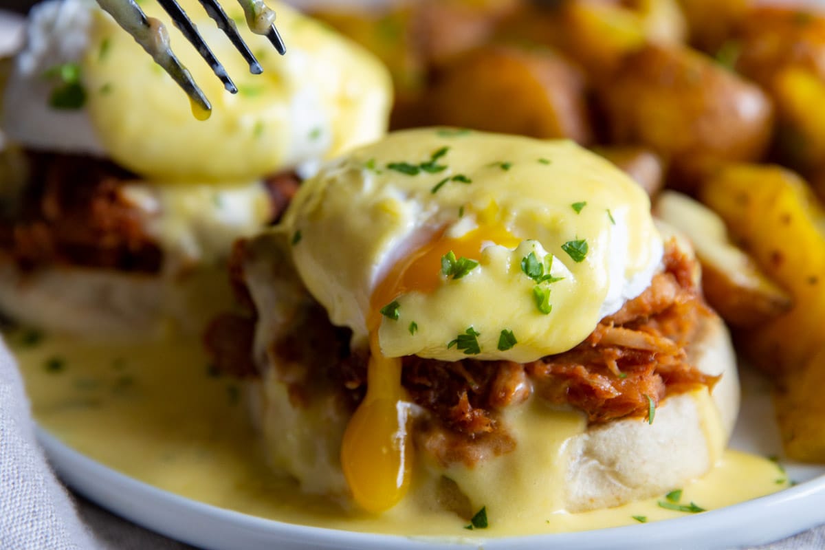 Pulled pork eggs benedict with a side of breakfast potatoes.