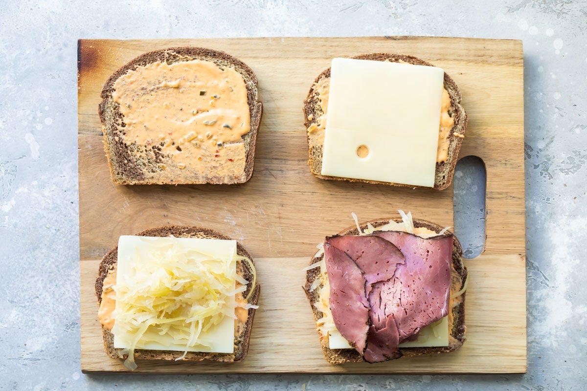 Assembling a reuben sandwich on a cutting board.