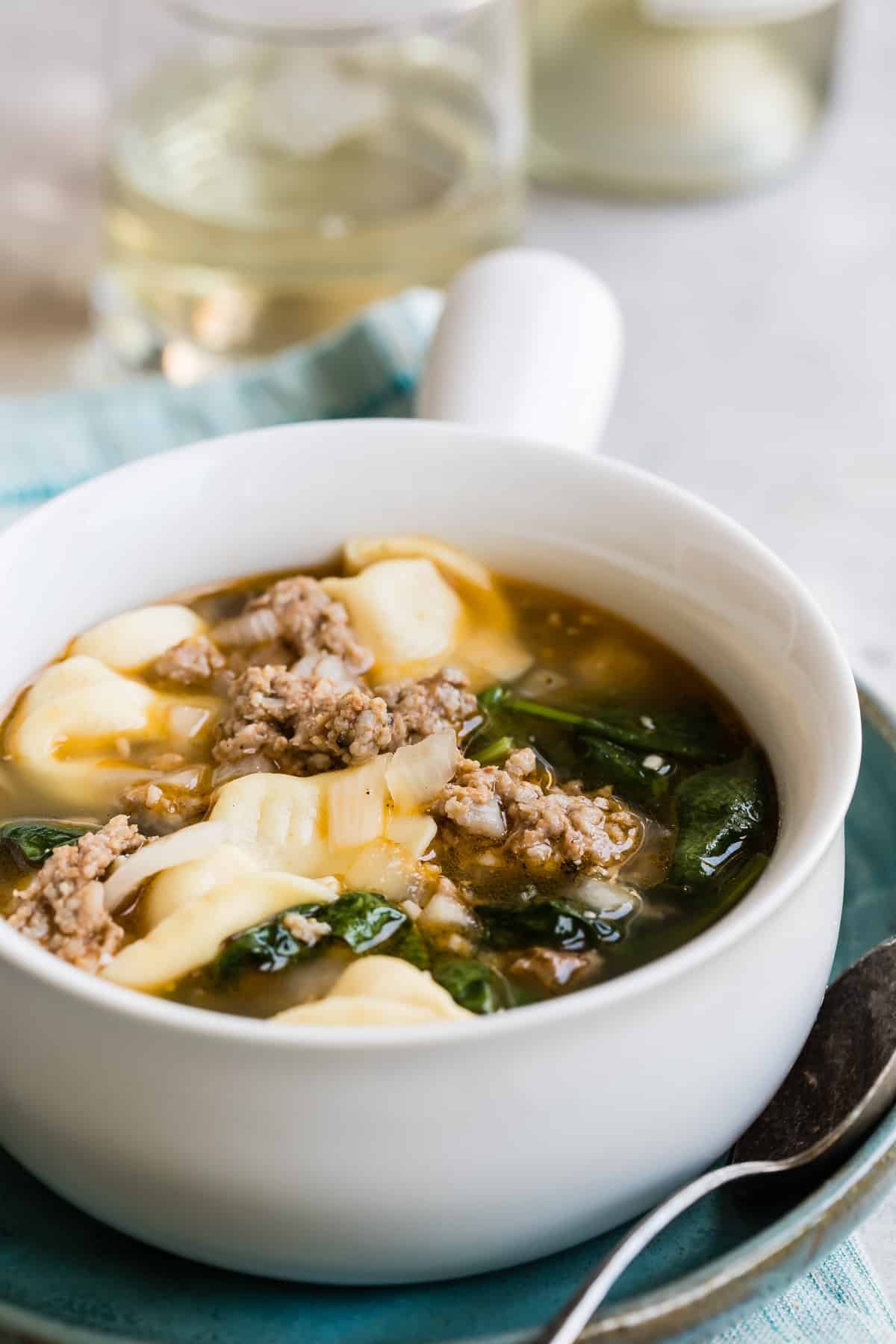 Sausage tortellini soup in a white bowl.