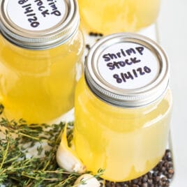 Three jars of shrimp stock on a white platter.