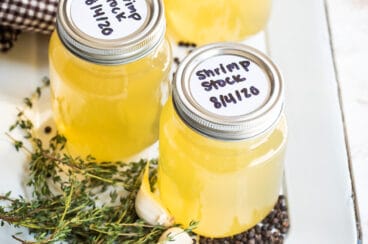 Three jars of shrimp stock on a white platter.