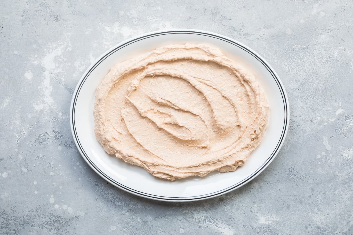Taco dip base spread out on a white platter.