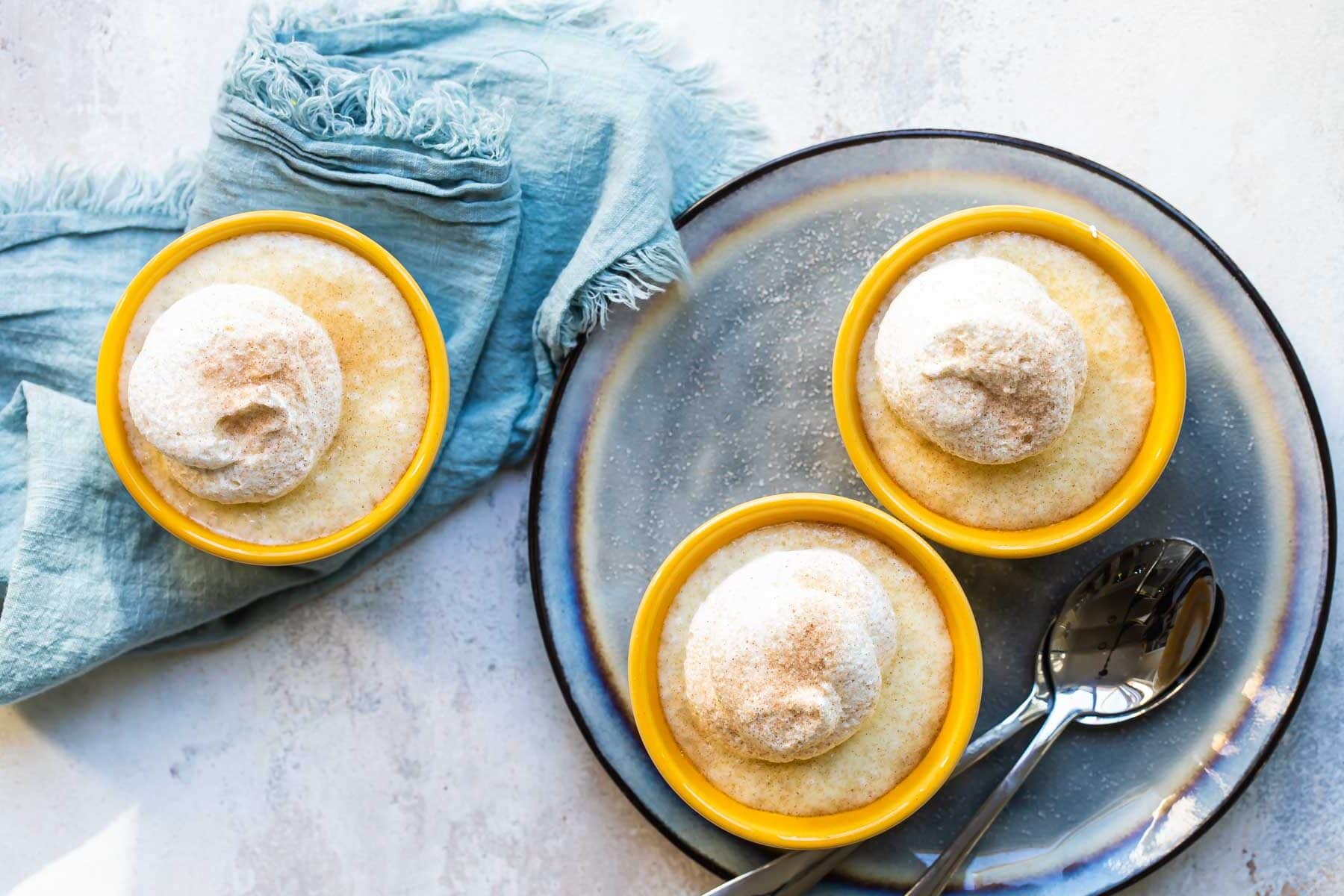 Three bowls of tapioca topped with whipped cream.